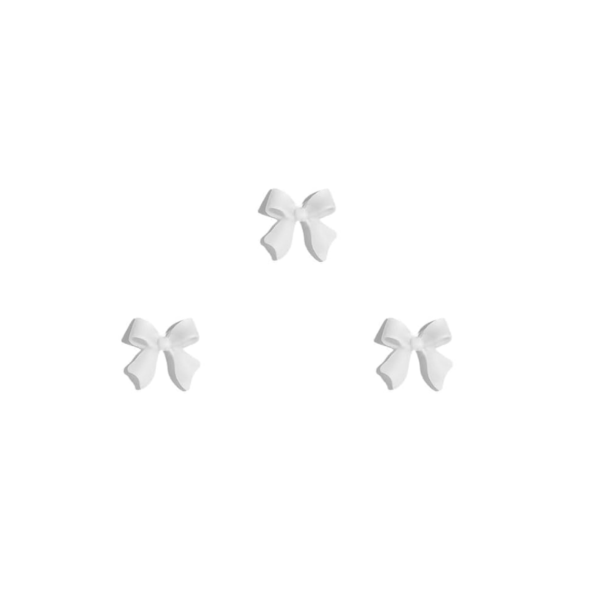 Set of three white bow-shaped nail charms on a white background